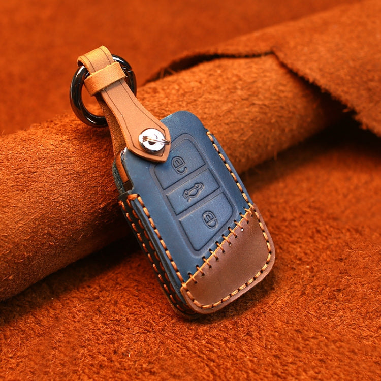 Blue leather key cover with brown trim, metal ring, stitched edges, and button panel