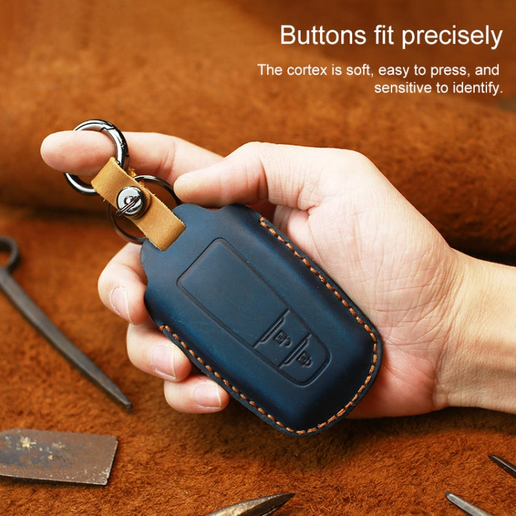 Leather key cover in dark blue with two-button panel, held in a hand.