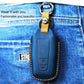 Leather key cover in dark blue with two-button panel and keyring loop on jeans.