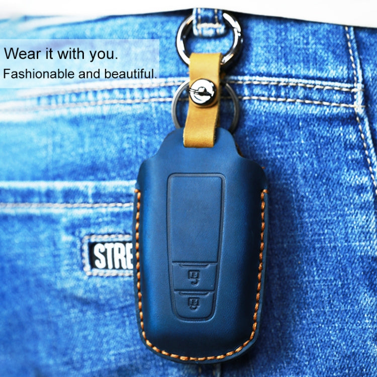 Leather key cover in dark blue with two-button panel and keyring loop on jeans.