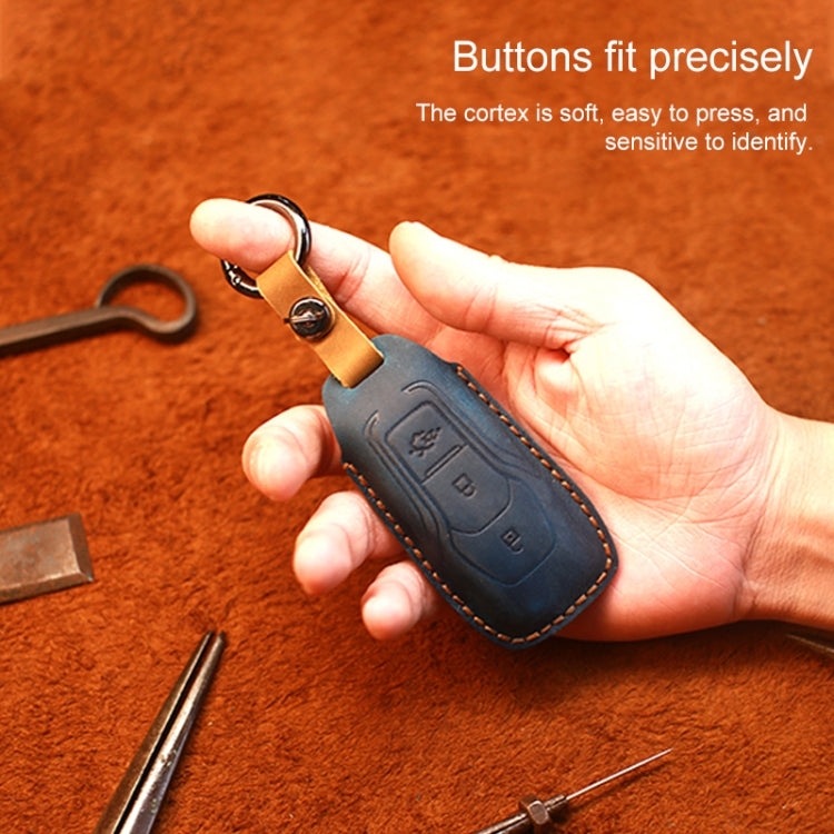 Blue leather key fob cover held in hand, with keyring and stitched trim