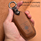 Brown leather key fob protective case with metal key ring, held in hands