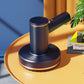 Blue handheld cordless vacuum on round charging base with angled nozzle canister