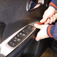 Hands installing a black window master switch on a car door panel