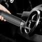 Hand holding handheld vacuum cleaner nozzle against car wheel area, dark gray