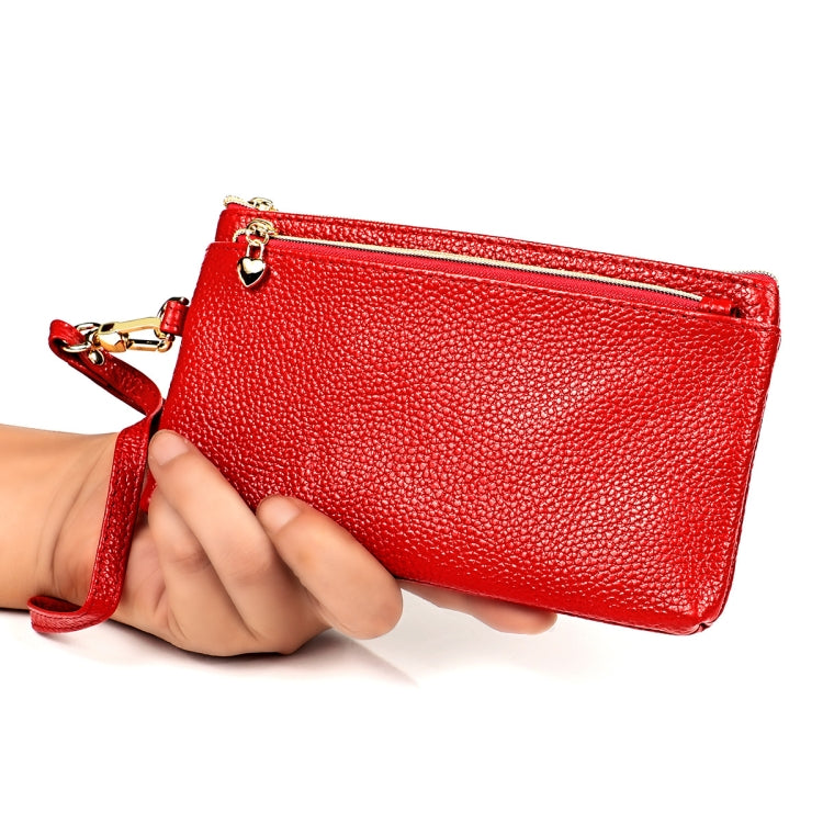 Red pebbled leather zip coin purse with wrist strap, held in hand with gold hardware.