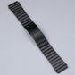 Black stainless steel watch strap with ribbed link segments and buckle end