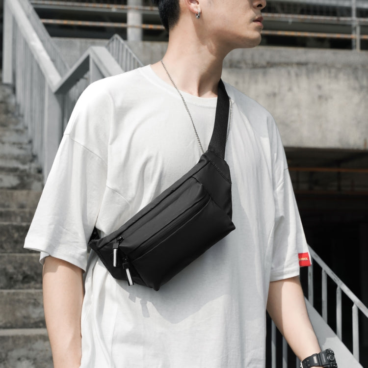 Black crossbody waist bag with zip pocket worn with adjustable strap