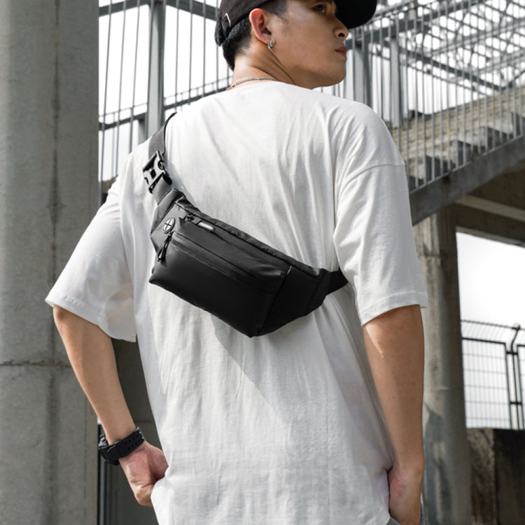Black adjustable waist bag worn on chest with zip front pocket and strap