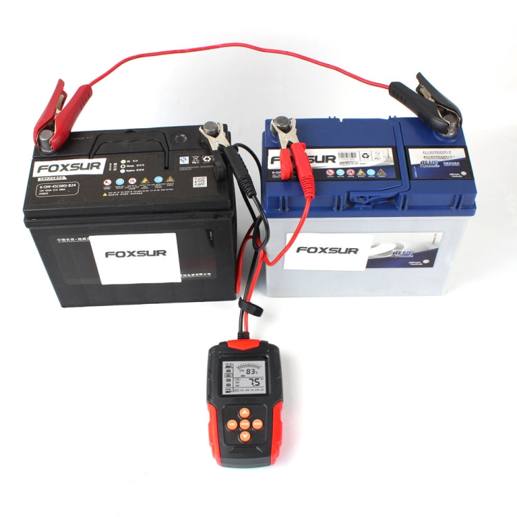 Car battery tester with alligator clamp leads connected to two batteries, handheld display