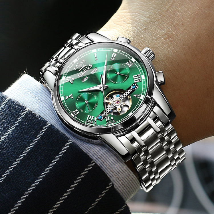 OLEVS men’s watch on wrist with green dial, roman markers, and steel bracelet