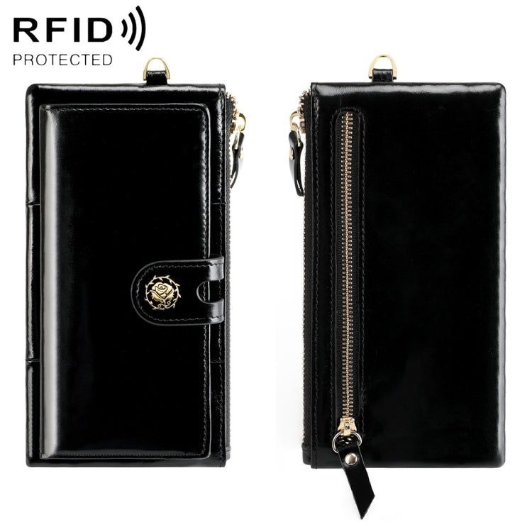 Black oil-wax wallet with snap button strap and gold zipper; wrist strap loop.