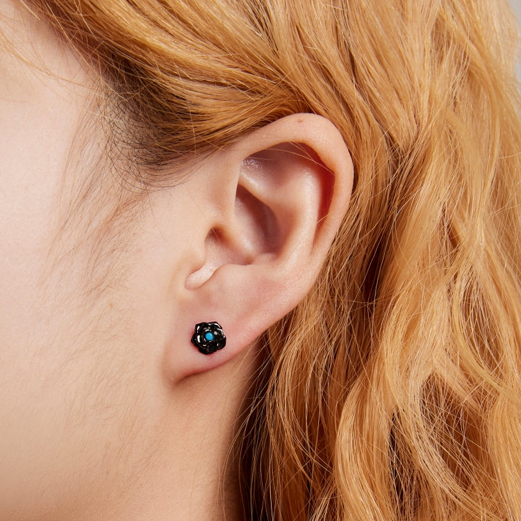 Black rose stud earrings on model, blue center gemstone