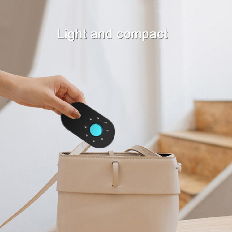 Compact black detector held above a bag, with a glowing blue status light.