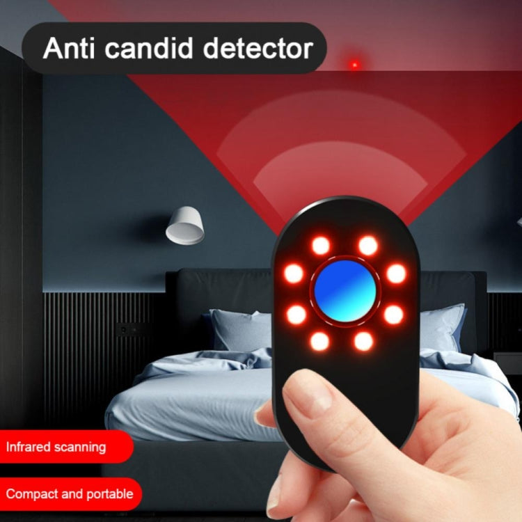 Black portable detector with red LED ring and blue center, held in a hand.