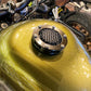Motorcycle fuel tank cap with black mesh grille on a round metal base