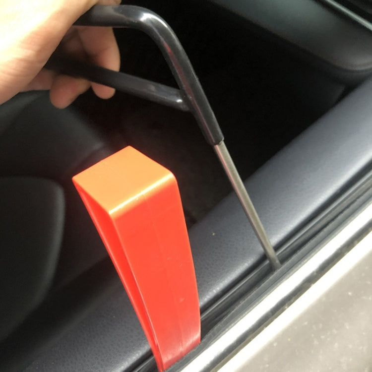 Red-handled dent repair hook tool held against car door panel seam