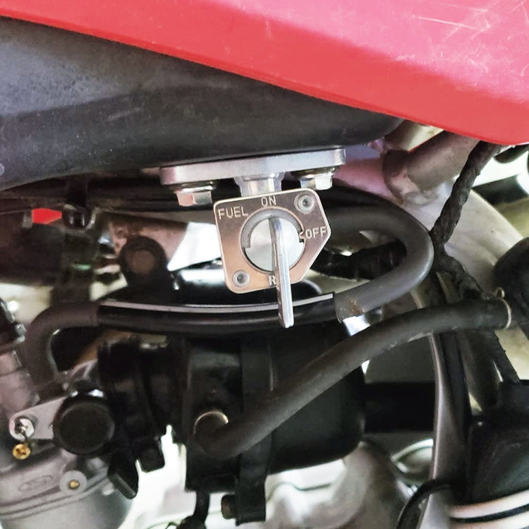 Installed motorcycle fuel petcock with ON/OFF selector and metal lever, close-up