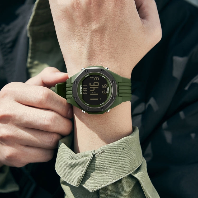 Green digital luminous watch on wrist with dark LCD and ribbed silicone strap