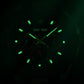 Dark watch dial with luminous green hands and hour markers