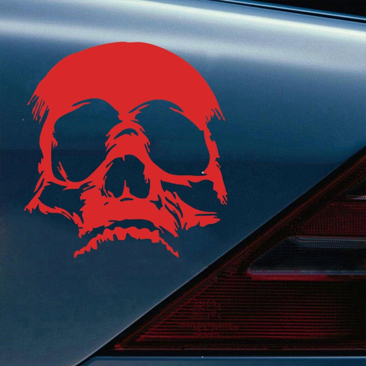 Red evil skull decorative sticker on car fender with white facial highlights.