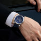 Blue leather-strap mechanical watch worn on wrist with luminous starry dial.