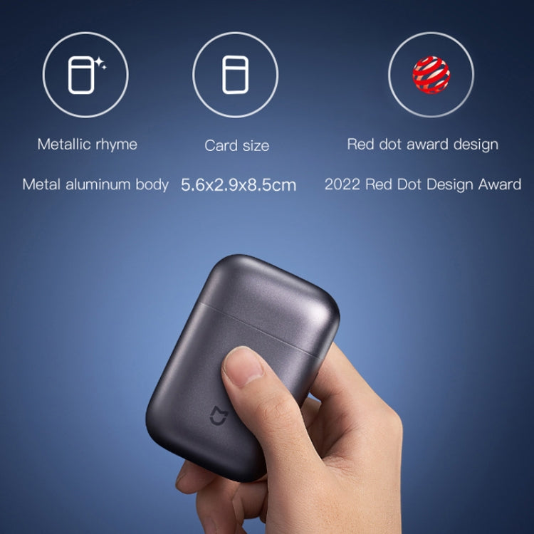 Electric shaver in dark finish held in hand, rounded compact body design