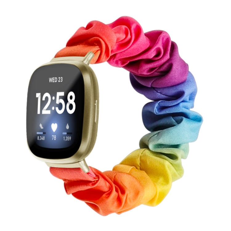 Rainbow cloth watch band with bright multicolor scrunch pattern; smartwatch shown.