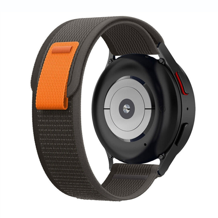 Black nylon loop watch band with orange accent tab and textured weave, shown on watch