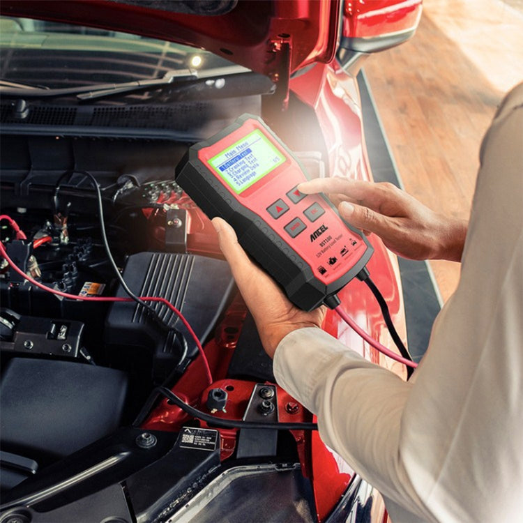 Hand holding red-and-black 12V battery tester connected to car battery terminals