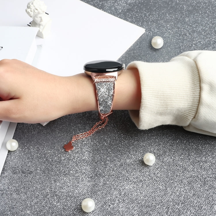 Rose gold rhinestone watch strap with chain and clover charm worn on wrist
