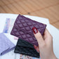 Dark purple quilted phone card holder with snap flap, held in a hand