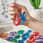 Hand holding colorful resin letter keychains; tray filled with matching alphabet shapes