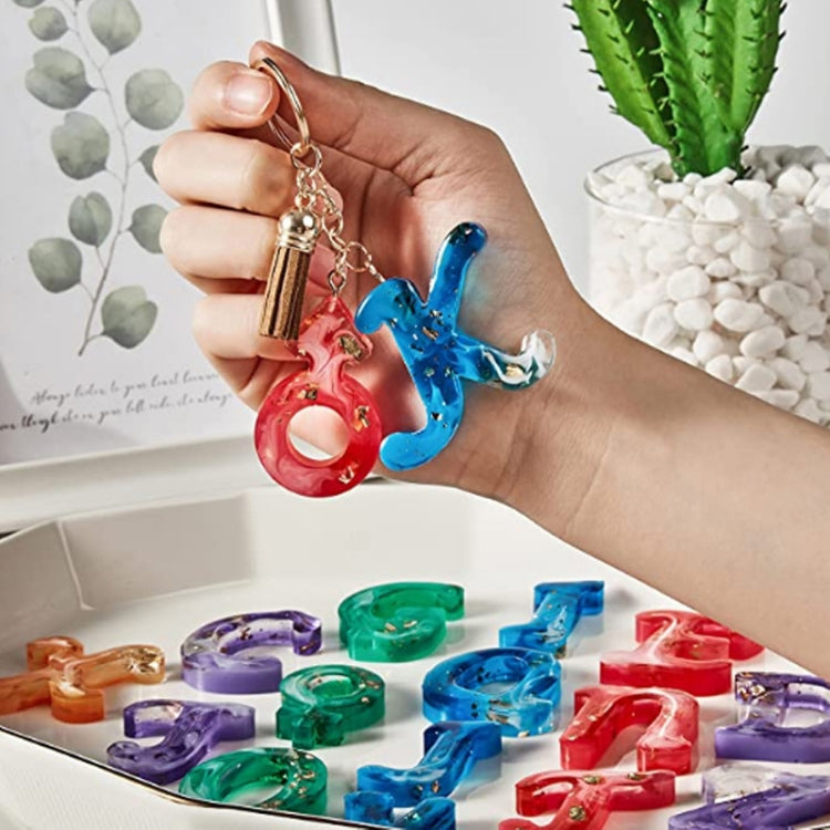Hand holding colorful resin letter keychains; tray filled with matching alphabet shapes