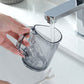 Clear mouthwash cup with side handle, held near faucet with water