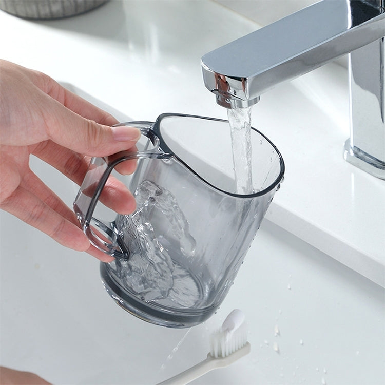Clear mouthwash cup with side handle, held near faucet with water