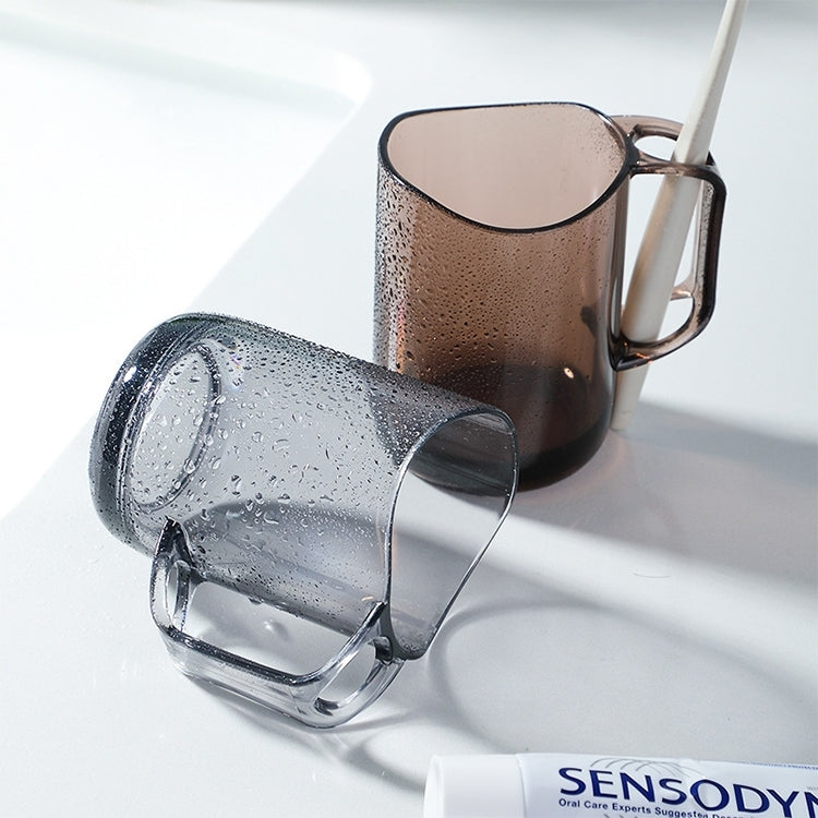 Transparent mouthwash cup with side handle, water droplets on surface