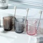 Clear acrylic mouthwash cup set with toothbrush bristles in handle slots