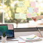 Hand placing colorful sticky notes on a window, desk notes ready to write