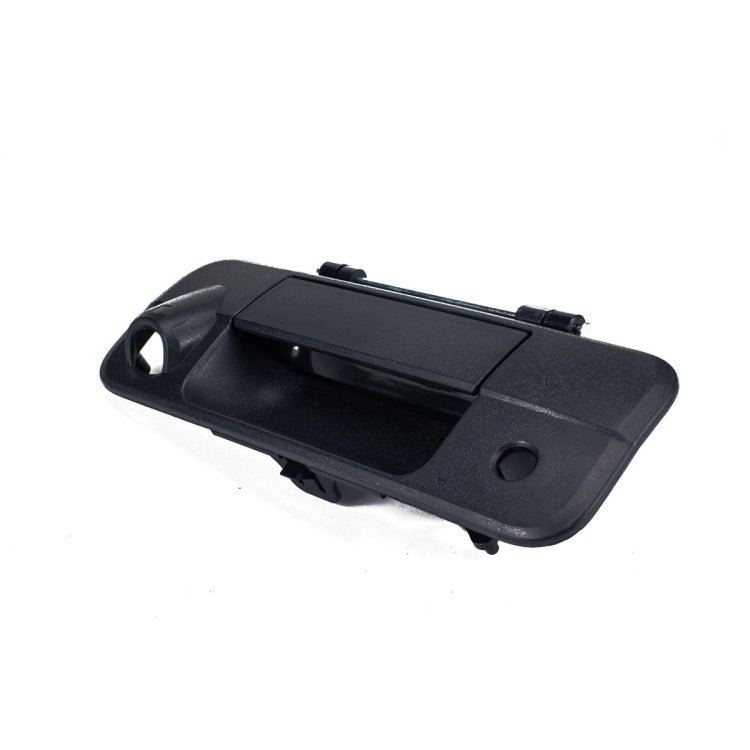 Black car tailgate handle exterior with circular mounting hole and latch recess