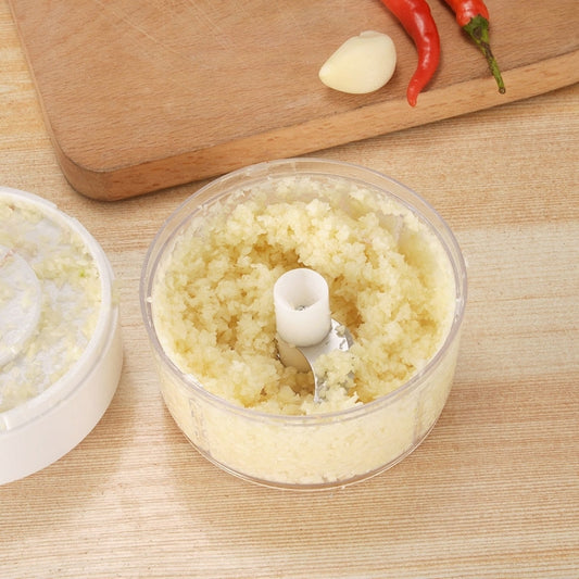 Transparent mini garlic cutter bowl with chopped garlic inside and garlic clove nearby