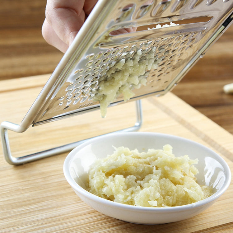 Stainless steel grater releasing grated potato into a white bowl