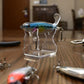 Transparent fishing lure stand holding a blue minnow lure with treble hooks