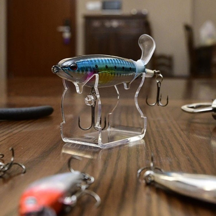 Transparent fishing lure stand holding a blue minnow lure with treble hooks