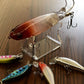 Clear fishing lure display stand with hook holders, showing lures around it