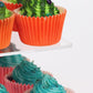 Orange and green cupcakes on clear acrylic tiers of a 4-tier cupcake stand