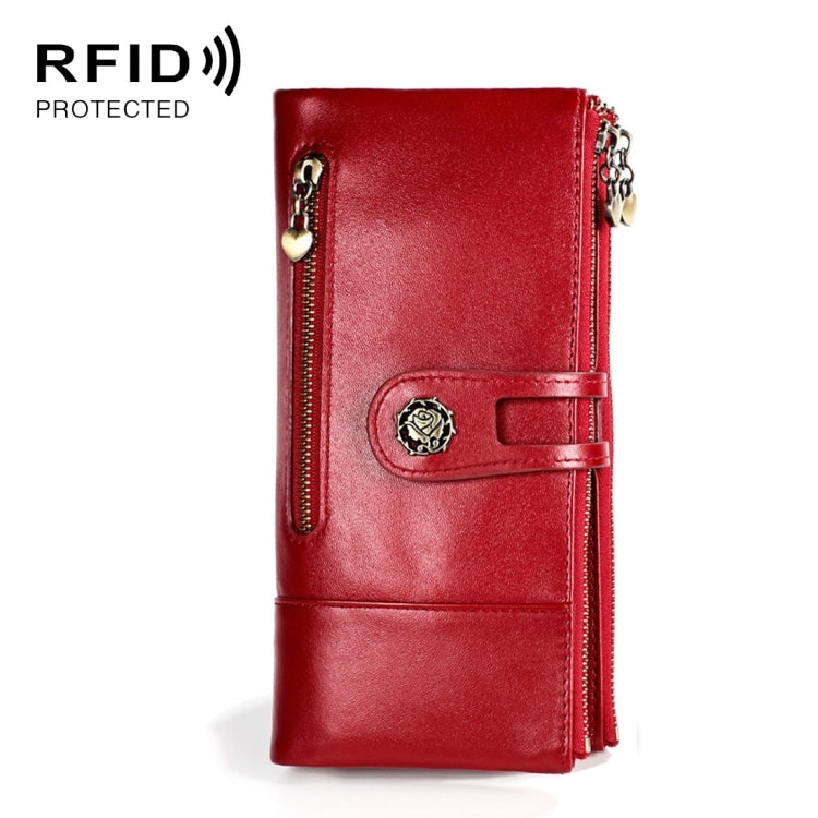 Red leather lady wallet with front strap, decorative badge, and zip coin pocket.