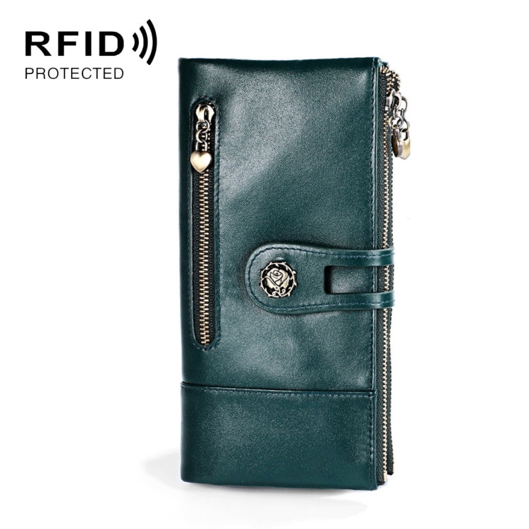 Dark teal leather lady wallet with front strap, decorative badge, and zip pocket detail.