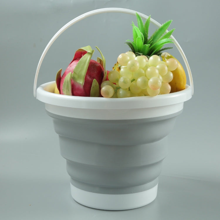 Light-colored silicone folding bucket with handle, filled with fruit and greens
