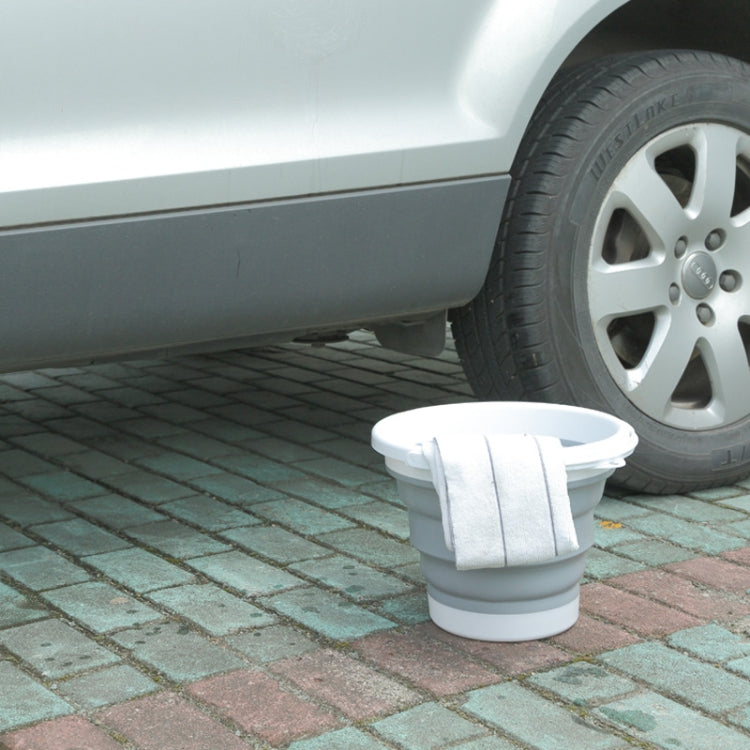 White silicone folding bucket with foldable rim, placed on paved ground